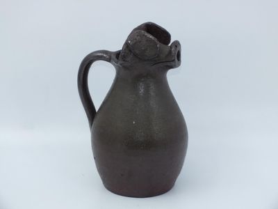 a black vase with a handle on a white surface