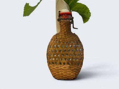 a wicker vase with a flower in it on a table