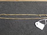 a gold chain with a white tag on it