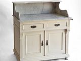 une armoire blanche avec un plan de travail en marbre, montée sur roulettes