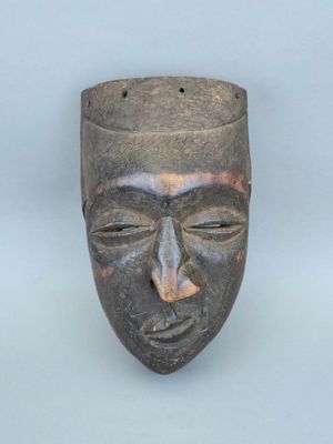 gros plan d'un masque en bois sur une surface blanche