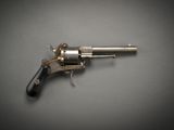 un gros plan d'un pistolet posé sur une table, sur fond gris