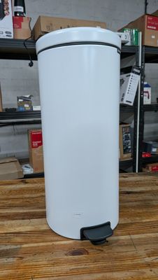 une poubelle blanche posée sur une table en bois