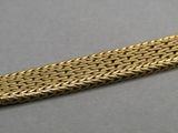 a close up of a gold chain bracelet on a gray surface