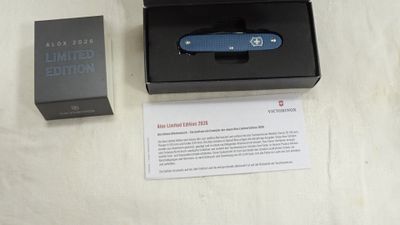 un petit couteau bleu dans une boîte noire posée sur une table