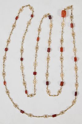chaîne en or ornée de perles en cornaline et de perles de verre rouges sur fond blanc