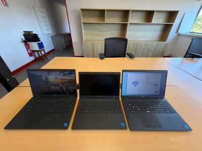 trois ordinateurs portables posés sur une table dans une pièce