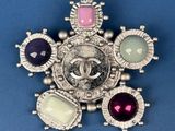 silver broochle with multi colored stones on a blue background