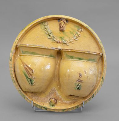 une image représentant un vase jaune orné de deux gros seins