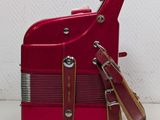 a red suitcase with a brown strap on top of it