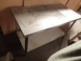 une petite table avec un plateau en métal, dans un coin de la pièce