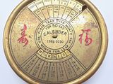 une horloge dorée, ornée d'inscriptions en chinois sur un fond blanc
