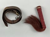 a picture of a leather belt with a red handle and some hair
