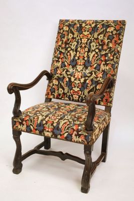 an old chair with a floral upholstered back and arms