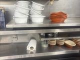 many plates and pans on the shelf in the kitchen
