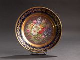 une assiette décorée de fleurs, posée sur un socle