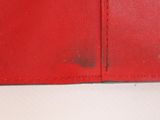 someone is holding a red leather wallet with a black spot on it