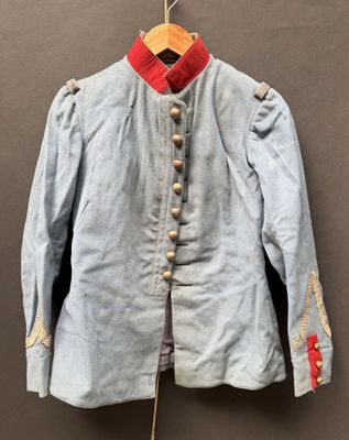 Une vieille veste bleue à col rouge est suspendue à un cintre.