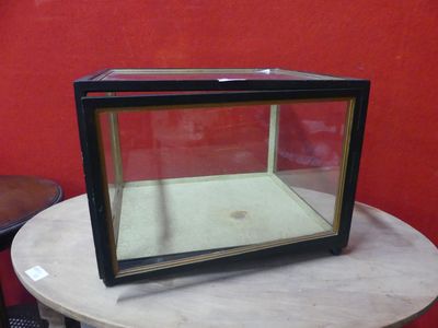 a glass display case sitting on a table in front of a red wall