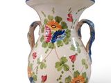 a white vase with a blue handle and flowers on it