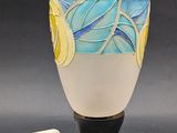 a white vase with a blue and yellow design on it next to a white device