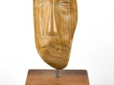 une photo d'une sculpture en bois représentant un visage, posée sur un socle en bois