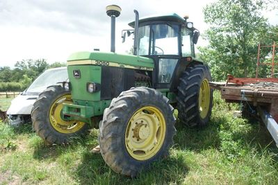 a tractor that is sitting in the grass near a trailer