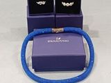 boîte à bijoux violette contenant deux boucles d'oreilles en argent et un bracelet bleu