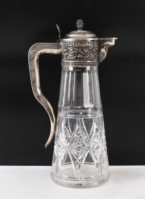 un pichet en verre plaqué argent muni d'une anse, posé sur une table