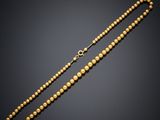 a gold beaded necklace on a black background