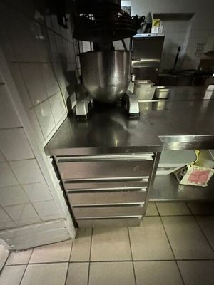 dimly lit kitchen with stainless steel counter tops and a large mixer
