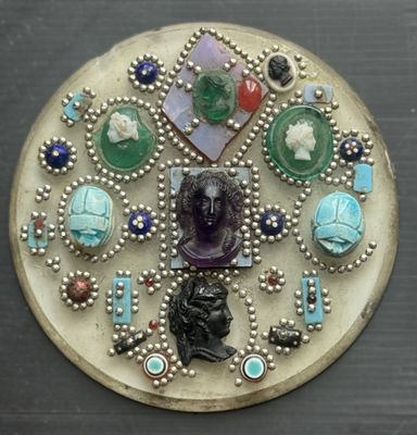 une photo d'une broche représentant une tête de femme entourée de bijoux