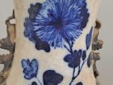 a vase with a blue flower on it sitting on a table