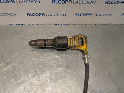 a close up of a drill on a metal surface with a sign in the background