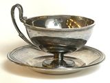 une tasse et une soucoupe en argent posées sur une soucoupe