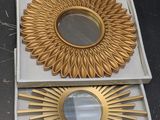 two gold sunburst mirrors are sitting on a table next to each other