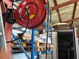 une borne d'incendie rouge posée sur un échafaudage bleu dans un entrepôt