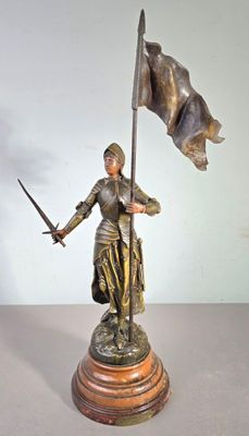 statue d'une femme tenant une épée et un drapeau, posée sur un socle en bois
