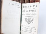 someone is holding a book in their hand near a bunch of books