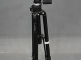 a black tripod sitting on top of a gray floor next to a camera