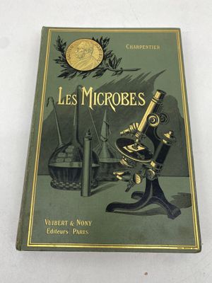 un vieux livre sur lequel est posé un microscope, posé sur une table