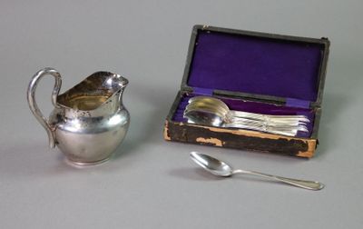 a silver pitcher next to a silver spoon and a purple box