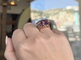 someone is holding a ring with an amethorate stone in it