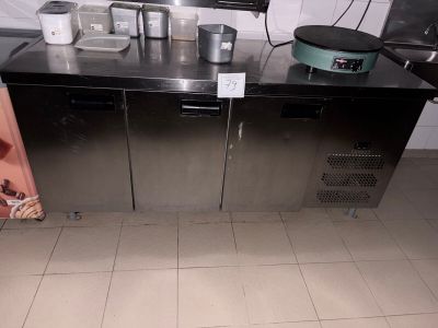 une cuisine équipée d'un évier et d'un plan de travail sur lequel sont posés des casseroles et des poêles