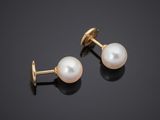 a pair of pearl and gold earrings on a black background