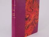 a purple book with a red cover sitting on top of a white surface