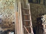 une échelle appuyée contre un mur, à côté d'un tas de bois