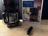 une cafetière noire et une boîte posées sur une table en bois