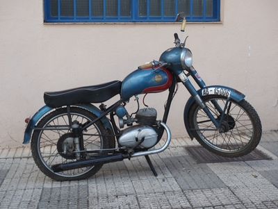 a blue motorcycle parked on the sidewalk in front of a building