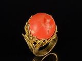 an image of a gold ring with a coral stone in the center